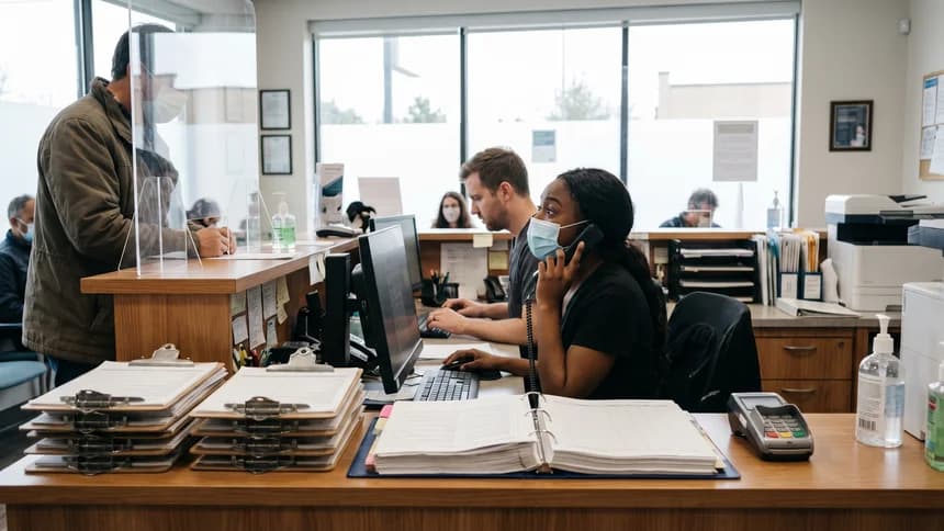 Busy medical practice front desk with staff juggling phones and check-ins