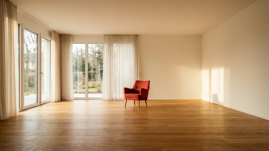 Empty renovated room with red accent chair and morning light