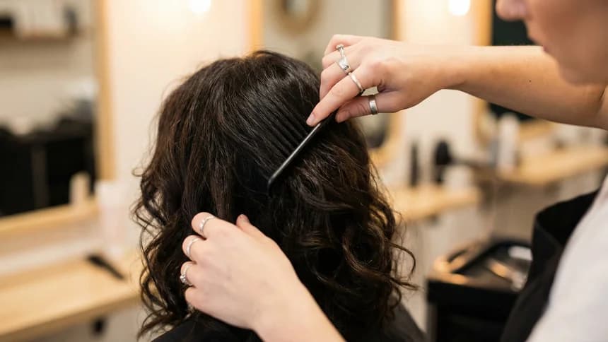 Stylist hands combing through client dark wavy hair