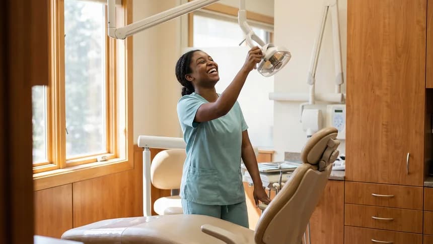 Dental hygienist laughing while adjusting overhead light