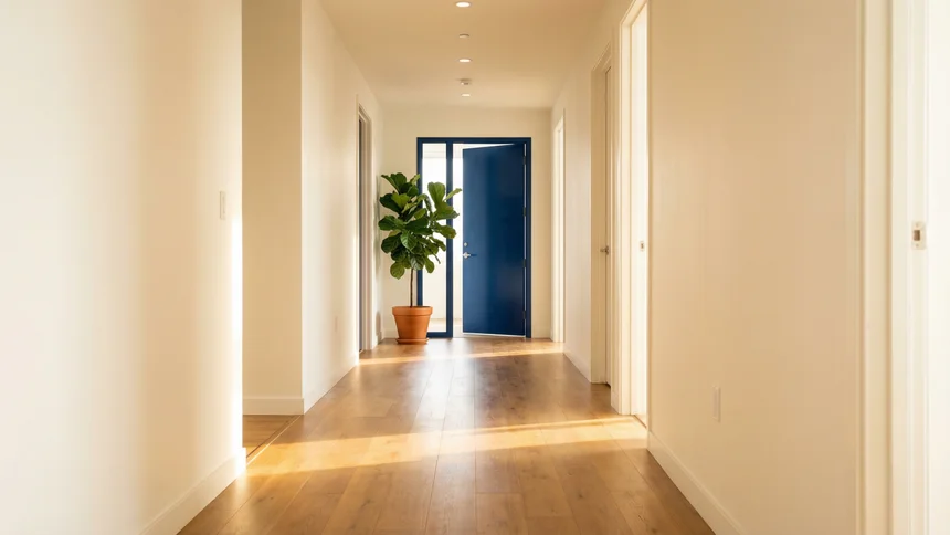 Open blue door at end of bright corridor with morning light